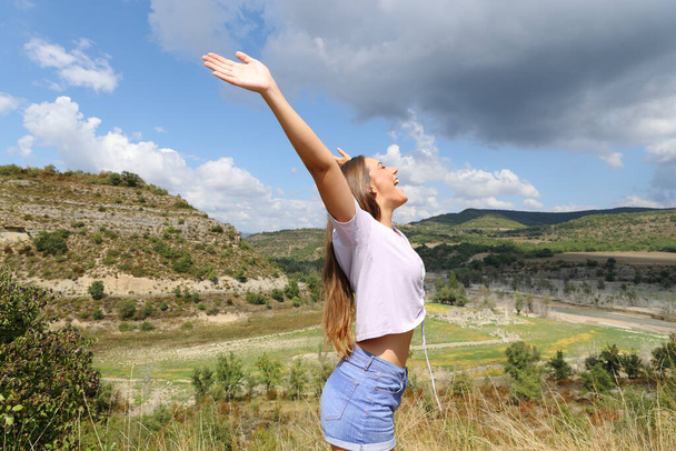 Euphoric woman outstretching arms in the mountain celebrating vacation - Foto, imagen