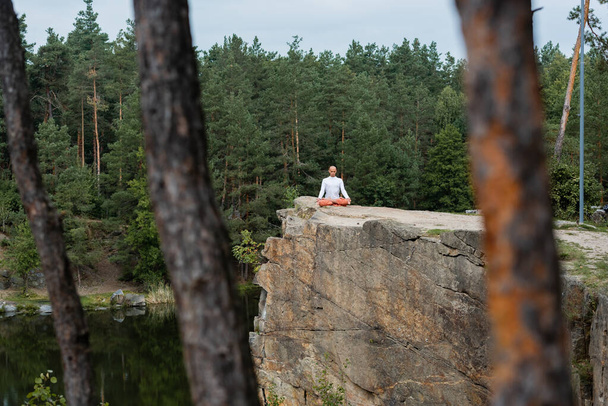 buddhalainen meditointi lootuksessa aiheuttaa kalliolla joen yli, sumentunut etualalla - Valokuva, kuva