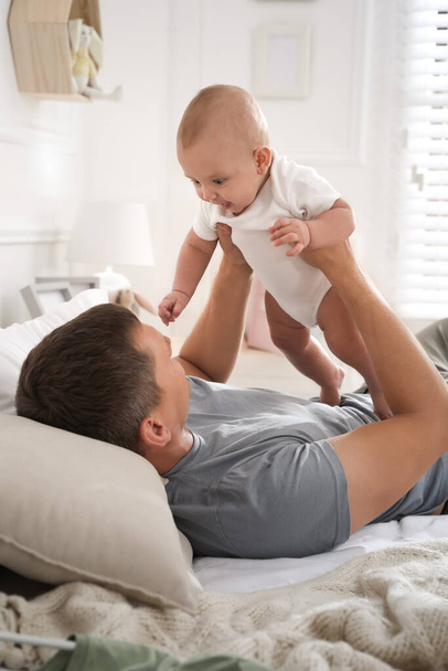 Father with his cute baby on bed at home. Happy family - Photo, image