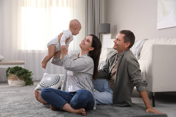 Happy family with their cute baby on floor in living room - Fotó, kép