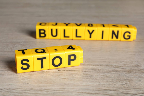 Frase Stop Bullying hecho de cubos amarillos con letras en la mesa de madera, primer plano - Foto, imagen