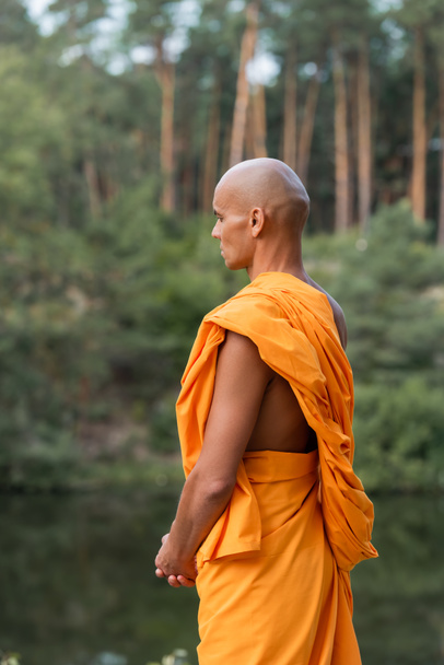 man in traditional buddhist robe meditating in forest - Photo, Image