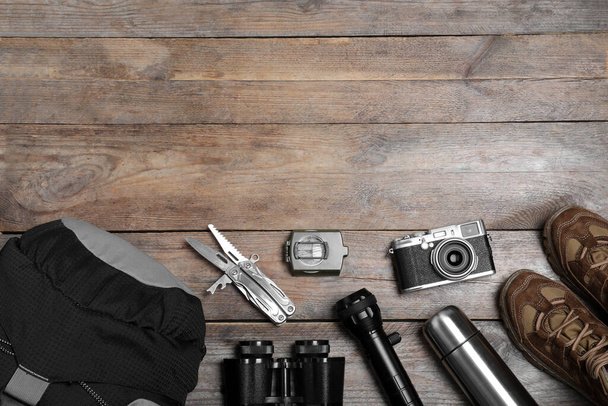 Flat lay composition with tourist backpack and other camping equipment on wooden background, space for text - Φωτογραφία, εικόνα