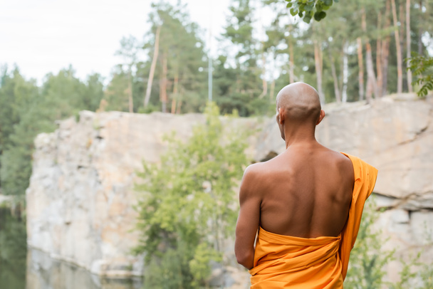 back view of hairless man in traditional buddhist robe meditating outdoors - Photo, Image