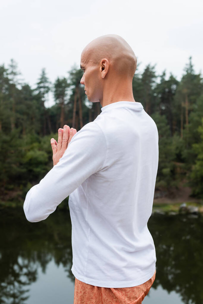 buddhist en sudadera blanca rezando y meditando al aire libre - Foto, imagen