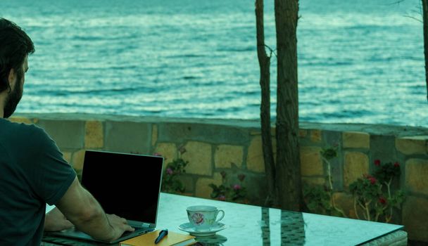 Concept van een professionele freelancer zakenman die werkt vanaf laptop van zomerhuis in vakantie, op afstand werken in vakantie, mobiliteit met technologie - Foto, afbeelding