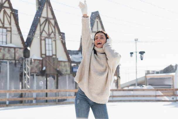 happy young woman in wireless headphone singing while listening music on ice rink  - Photo, Image