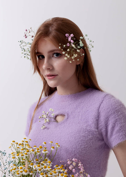 red-haired girl in 2000s clothes with a bouquet of flowers on a light background - Foto, Bild