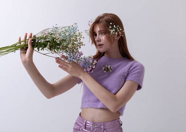 red-haired girl in 2000s clothes with a bouquet of flowers on a light background - Φωτογραφία, εικόνα