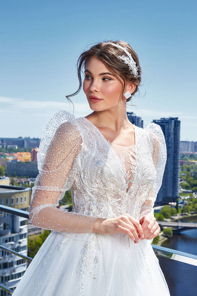 Beautiful tender young woman sexy brunette bride in a luxury white wedding dress lace chiffon Summer happiness awaits the groom before the wedding ceremony makeup accessory jewelry smile. - Foto, afbeelding