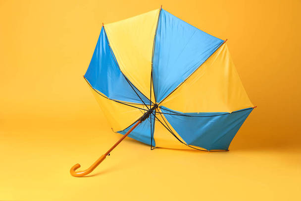Broken bright umbrella with wooden handle on yellow background - Fotografie, Obrázek