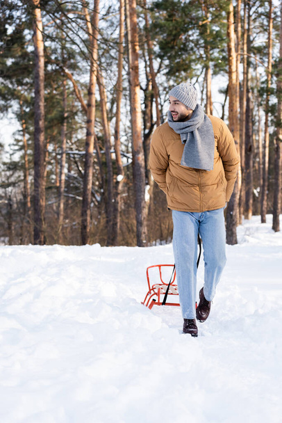 Bärtiger Mann zieht Schlitten im Winterpark  - Foto, Bild