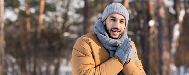 Hombre positivo en ropa de abrigo mirando a la cámara en el parque de invierno, pancarta  - Foto, imagen