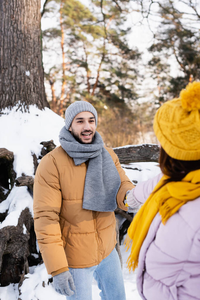 Smiling man holding hand of blurred girlfriend in winter park  - Valokuva, kuva