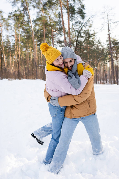 Cheerful couple embracing in snowy park  - Fotó, kép