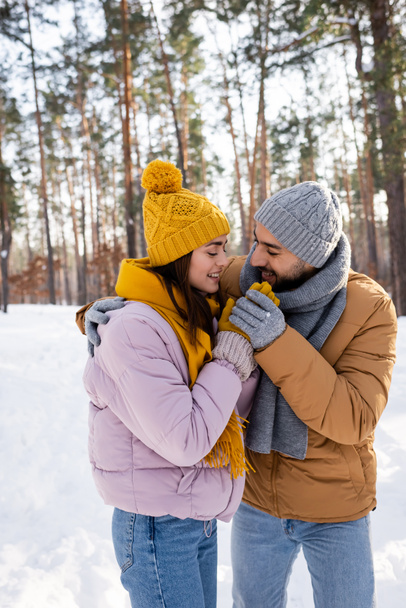 Smiling man hugging girlfriend and holding hands in winter park  - Fotó, kép