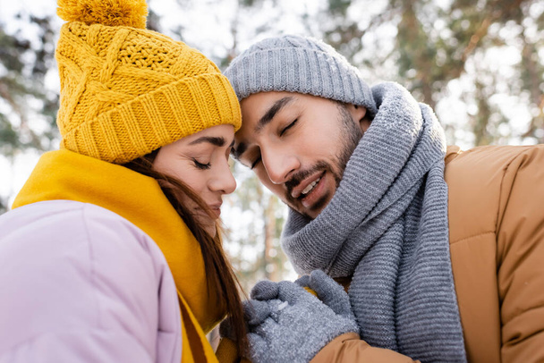 Smiling couple with closed eyes holding hands in winter park  - Foto, imagen