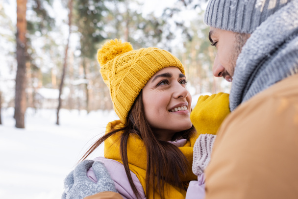 Smiling man hugging girlfriend in winter outfit outdoors  - Фото, зображення