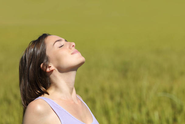 Profile of a woman breathing fresh air in a wheat field a sunny day - Zdjęcie, obraz