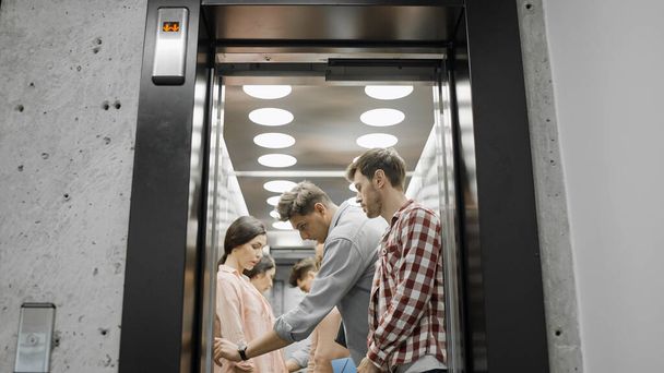 Young colleagues going inside elevator, office employees in business center - Foto, Imagem