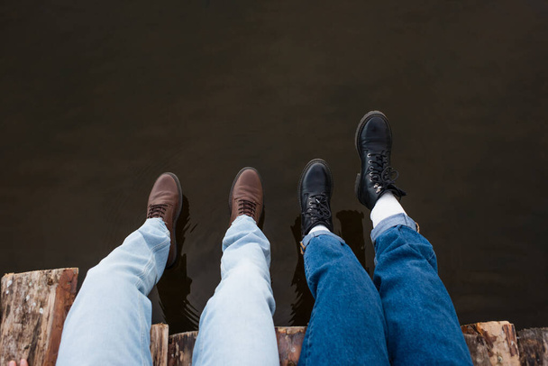Gekropt uitzicht van paar zitten op houten pier boven meer  - Foto, afbeelding