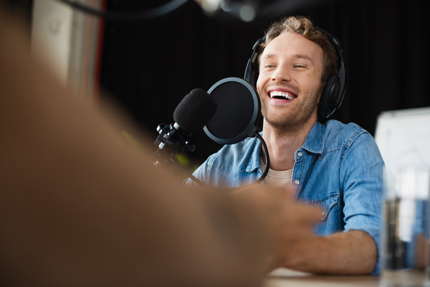 positive radio host in headphones laughing in studio  - Foto, Imagen