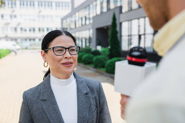 pozytywne Azji bizneswoman w okulary patrząc na rozmyte dziennikarz  - Zdjęcie, obraz