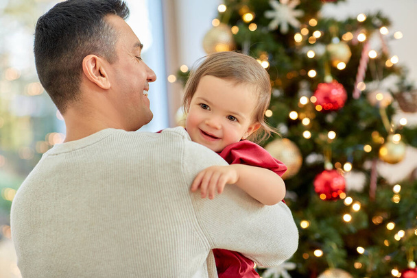 happy father and baby girl over christmas tree - 写真・画像