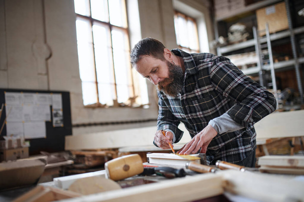 Portrait of mature male carpenter working on his product. Small business concept. - Fotó, kép