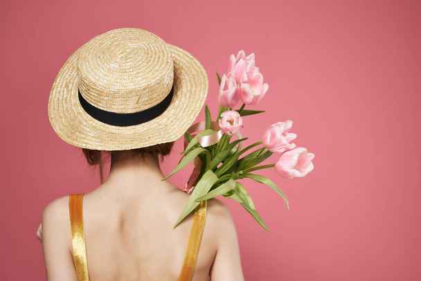 woman wearing a hat bouquet of flowers back view decoration pink background - Fotó, kép