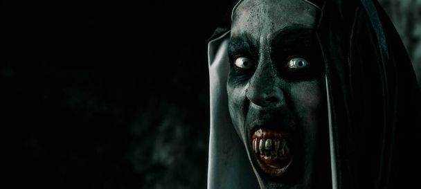 恐ろしい悪の修道女のクローズアップは、典型的な黒と白の習慣で、彼女と恐ろしい血の歯を示し、ウェブバナーやヘッダーとして使用するパノラマ形式で - 写真・画像