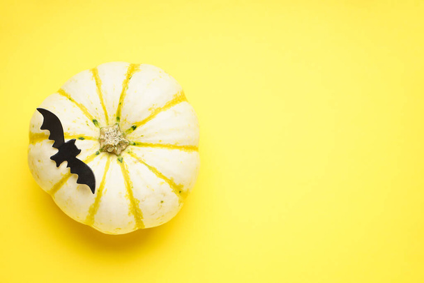 Concept d'Halloween. Citrouille d'Halloween et chauve-souris sur fond jaune, espace pour le texte. Pose plate. - Photo, image