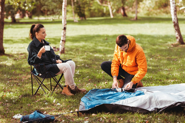 happy couple setting up tent outdoors - Φωτογραφία, εικόνα