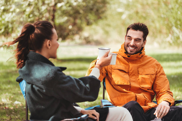 happy couple drinking tea at campsite - 写真・画像