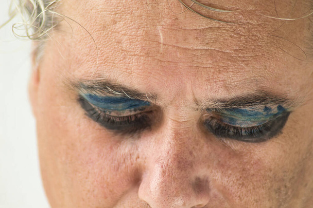 közeli kép egy homokos férfi szürke haj és festett szemek fehér háttér - Fotó, kép