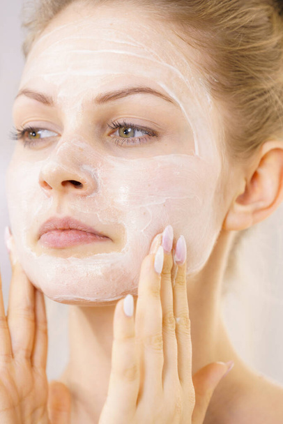 Mujer joven aplicando crema cosmética, mascarilla hidratante en su cara. Tratamiento de belleza. Cáscara. - Foto, Imagen