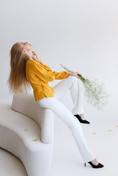 blogger modelo con estilo con flores en un sofá ligero. humor de moda - Foto, Imagen