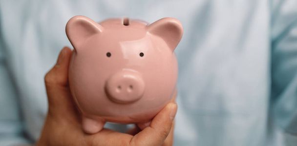 Business woman holding a piggy bank with coins. Coronavirus economic stimulus rescue package, superannuation, financial crisis concept - Photo, Image