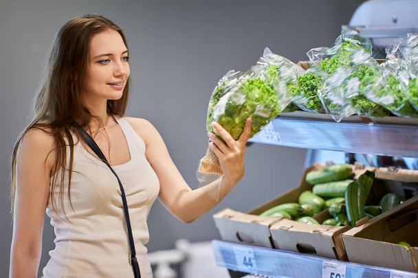 Young white woman chooses salad in supermarket. - Φωτογραφία, εικόνα