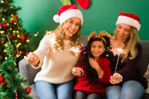 Close-up de uma família jovem multirracial se divertindo com um sparkler durante as férias de Natal  - Foto, Imagem