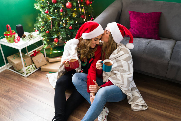 Χριστούγεννα μαζί σου. LGBT νεαρό ζευγάρι απολαμβάνοντας ένα φλιτζάνι ζεστή σοκολάτα μαζί κατά τη διάρκεια ενός κρύου πρωί των Χριστουγέννων - Φωτογραφία, εικόνα