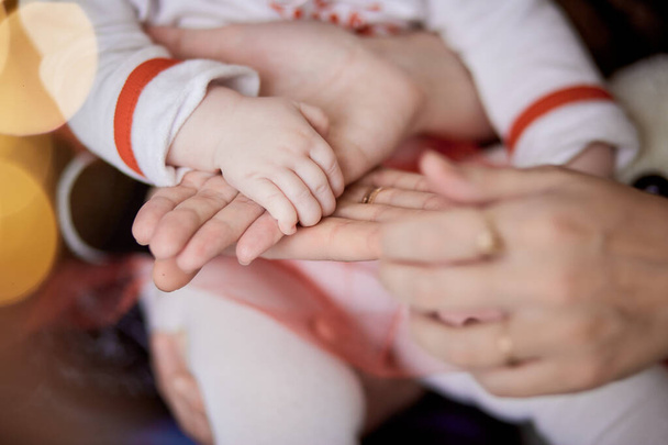 Family keeps hands together. Mother, father and little baby hands close up. Sweet home, tenderness and love together concept. High quality photo - Photo, Image