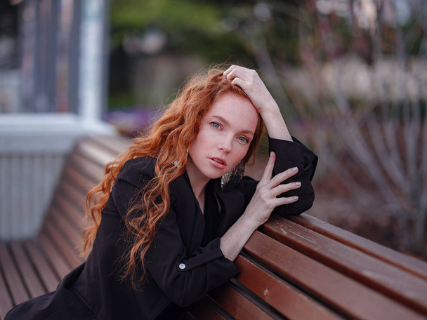 Ginger mladá žena chodí do jarního města. Obchodní dáma sedí na lavičce - Fotografie, Obrázek