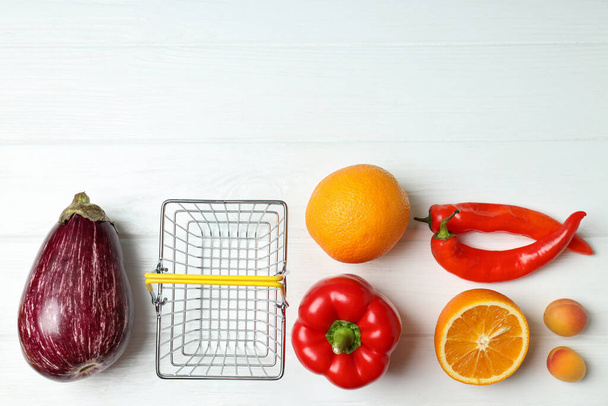 Καλάθι αγορών, λαχανικά και φρούτα σε λευκό ξύλινο τραπέζι - Φωτογραφία, εικόνα
