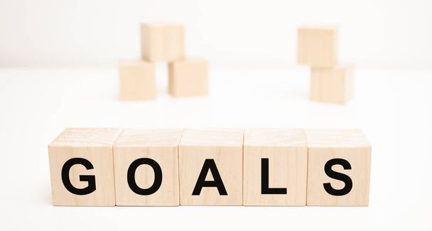 the word GOALS is written on a wooden cubes structure. blocks on a bright white background. - Фото, изображение