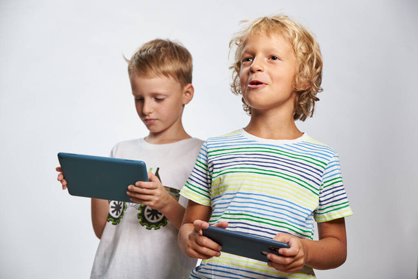 Two boy friend play online game on tablet and smartphone - Zdjęcie, obraz