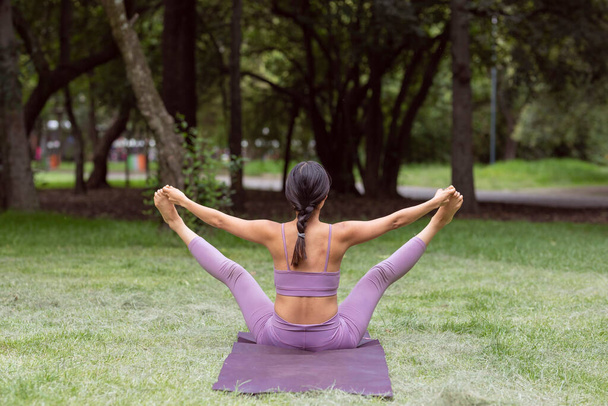 Meksikalı kadın yeşil çimenler üzerinde parkta yoga egzersizleri yapıyor. - Fotoğraf, Görsel
