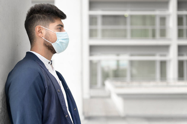 Bel giovanotto in piedi all'aperto in maschera medica. Concetto di coronavirus. - Foto, immagini