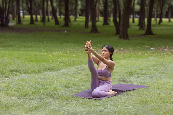 Meksikalı kadın yeşil çimenler üzerinde parkta yoga egzersizleri yapıyor. - Fotoğraf, Görsel