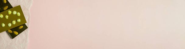 Шоколадний батончик з мигдалем та лісовими горіхами на паперовому фоні. Солодкість з горіхами. рожеве місце для вставки тексту. банер для розміщення на сайті
 - Фото, зображення